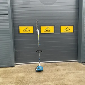 Petrol hedge trimmer standing upright against a grey industrial door with Warminster Tool Hire signs