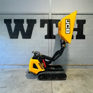 Yellow JCB tracked dumper with raised skip inside a warehouse