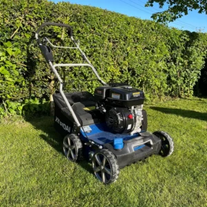 Petrol lawn scarifier on a grassy lawn beside a hedge