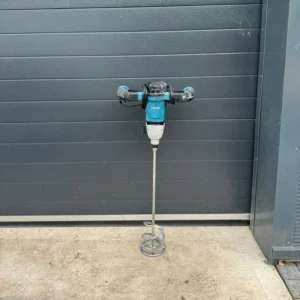 Electric paint mixer standing on a concrete floor against a dark wall