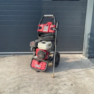 Petrol pressure washer on a concrete surface, with hose and spray lance attached