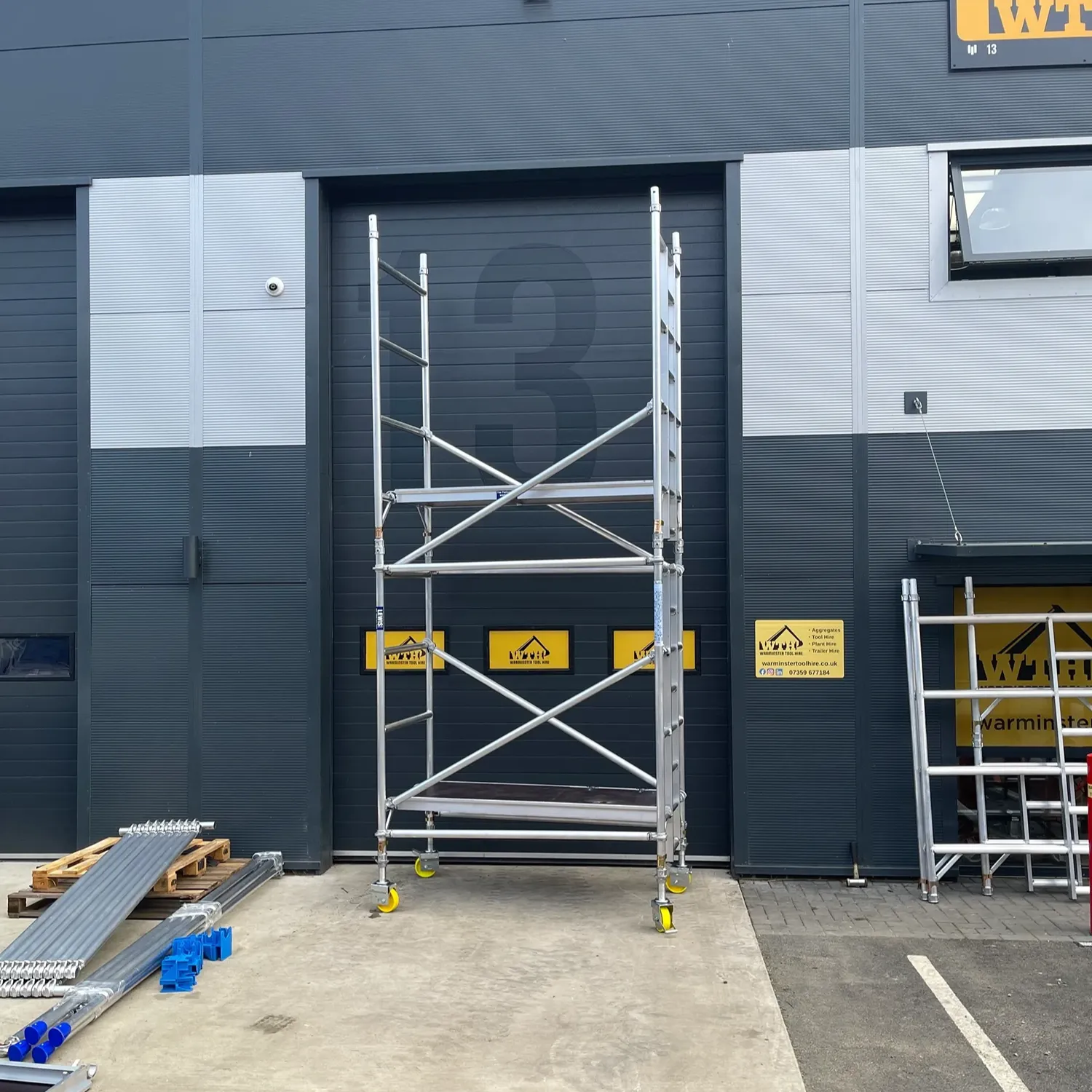 Scaffolding tower outside a warehouse unit with Warmister Tool Hire signs