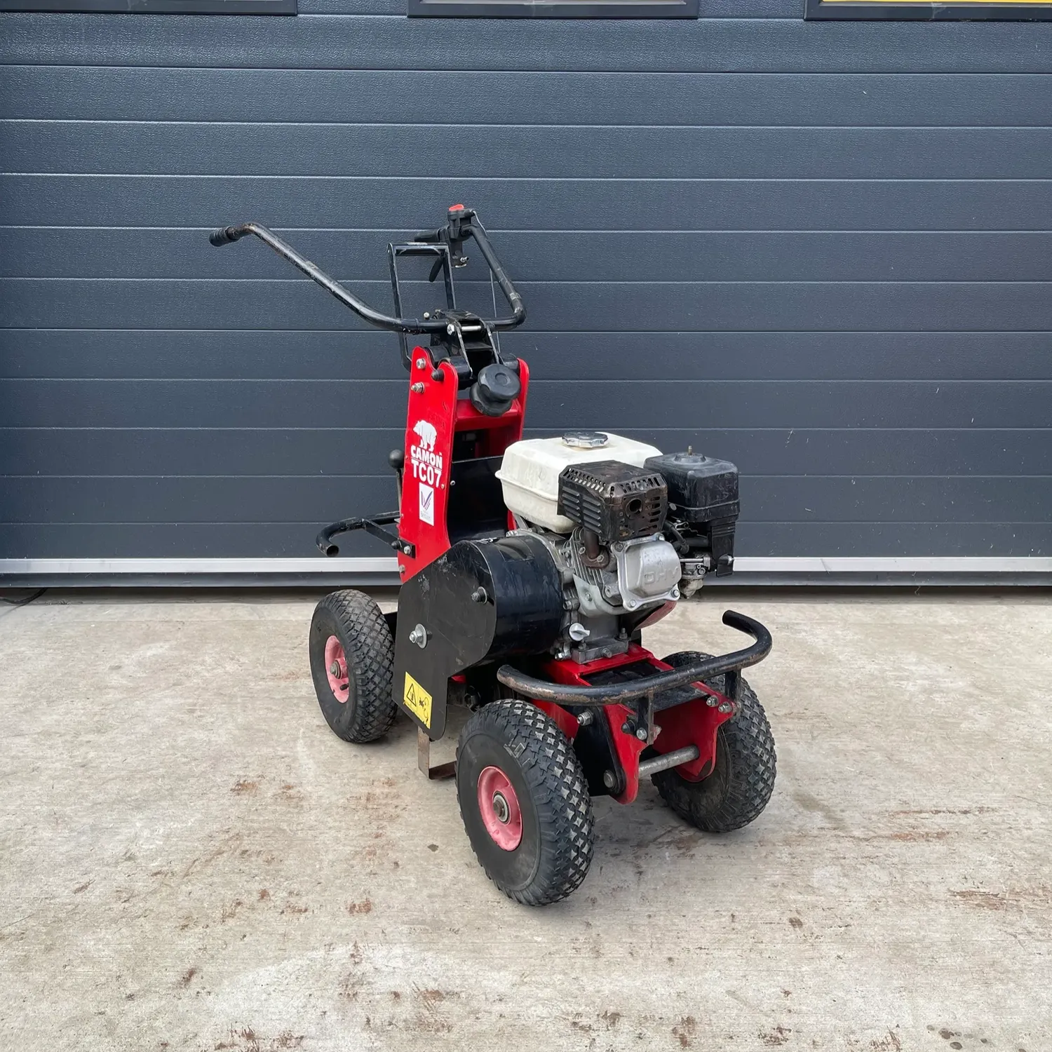 Four-wheeled petrol-powered garden machine with handlebars and engine